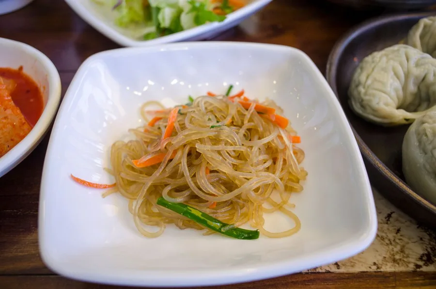 Prato de japchae, macarrão transparente com legumes